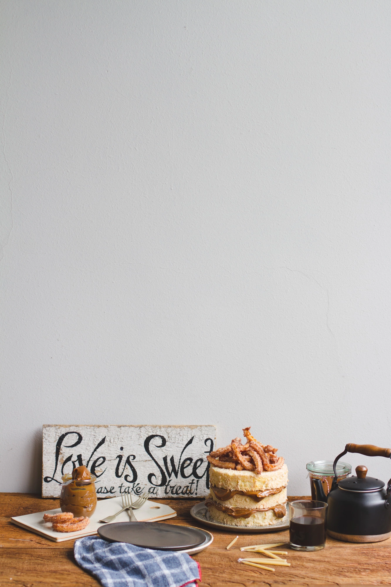 bolo de churros em uma mesa com um bule de café um copo com café e algumas decorações