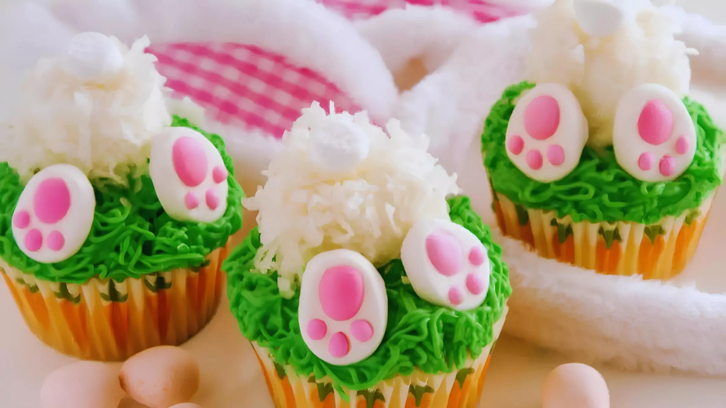 três cupcakes com decorações de coelhinho da páscoa.