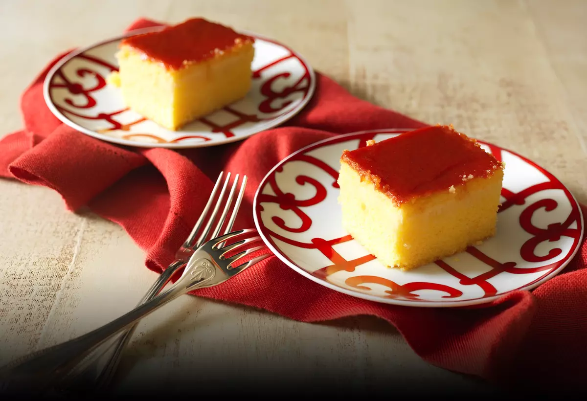 dois pratos com uma fatia de bolo de fubá cremoso com goiabada.