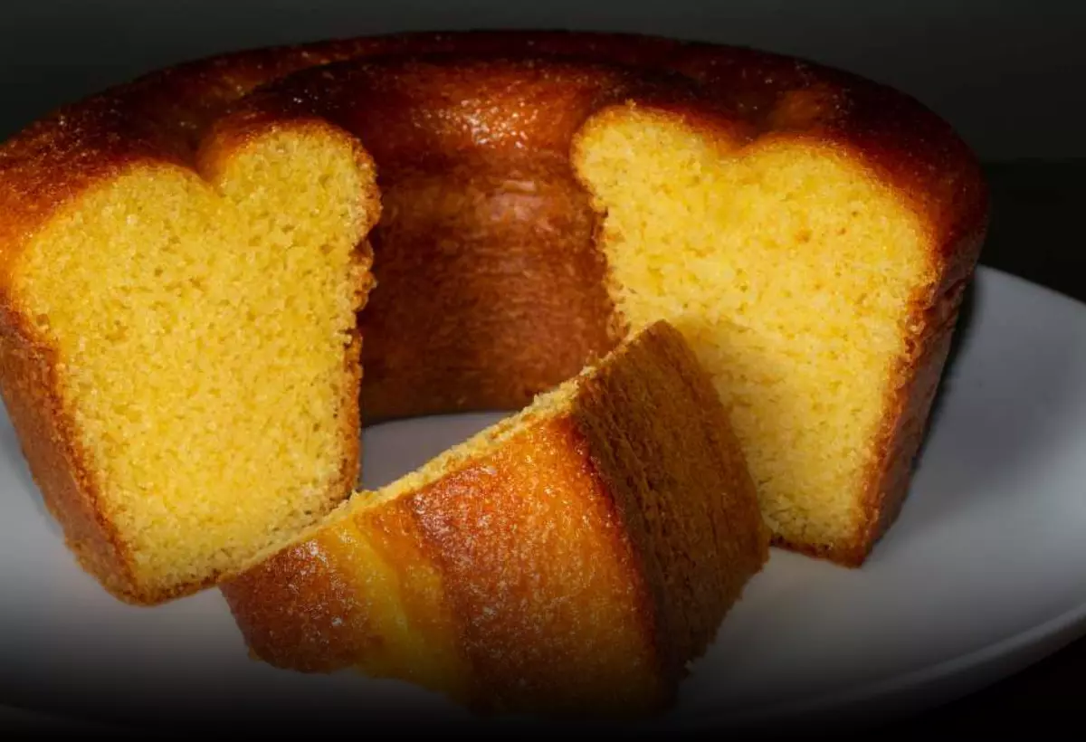 Um prato com um bolo de fubá com farinha de arroz fatiado.