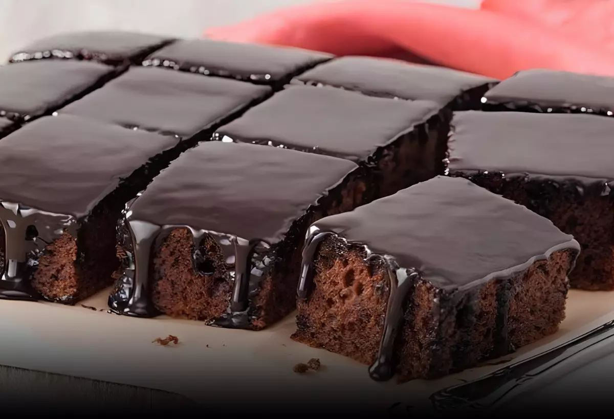 um bolo de nega maluca em pedaços com cobertura de chocolate em um prato.