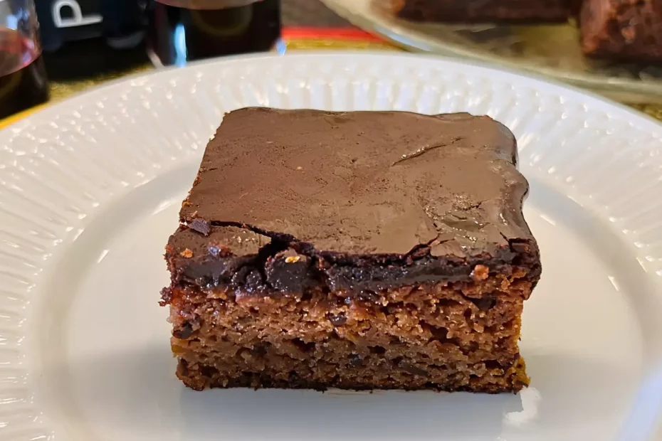 Um prato com uma fatia de bolo nega maluca com cobertura durinha.