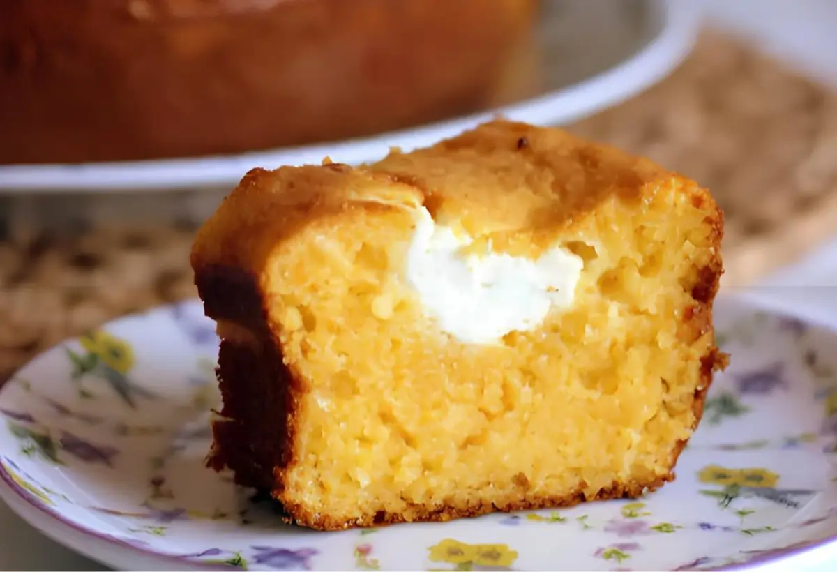 Um prato com um pedaço de bolo de flocão de milho com requeijão.