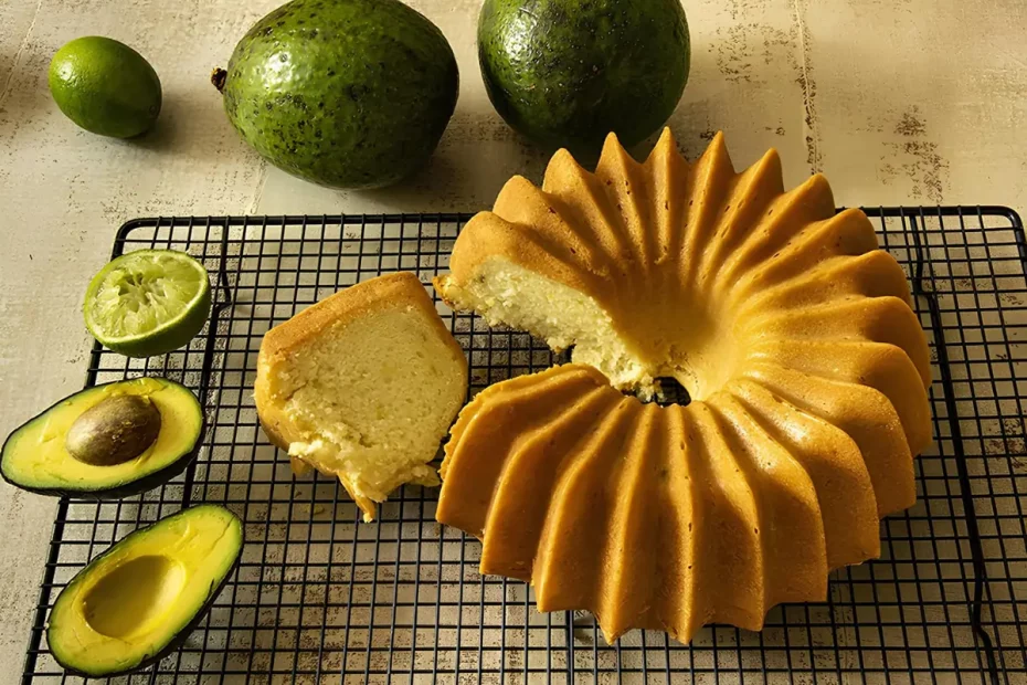 Um bolo fit de abacate e limão em um mesa, com abacates cortado ao lado para decorar.