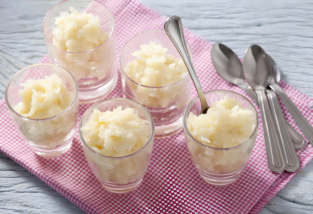 Copos com cocada cremosa em cima de uma mesa.