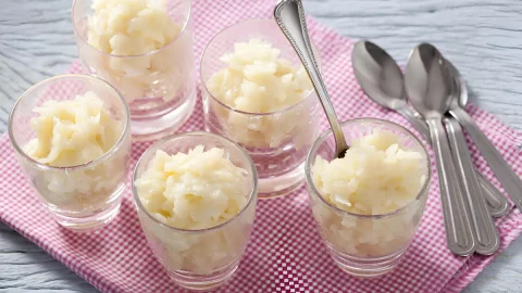 copos com cocadas cremosa em cima de uma mesa.