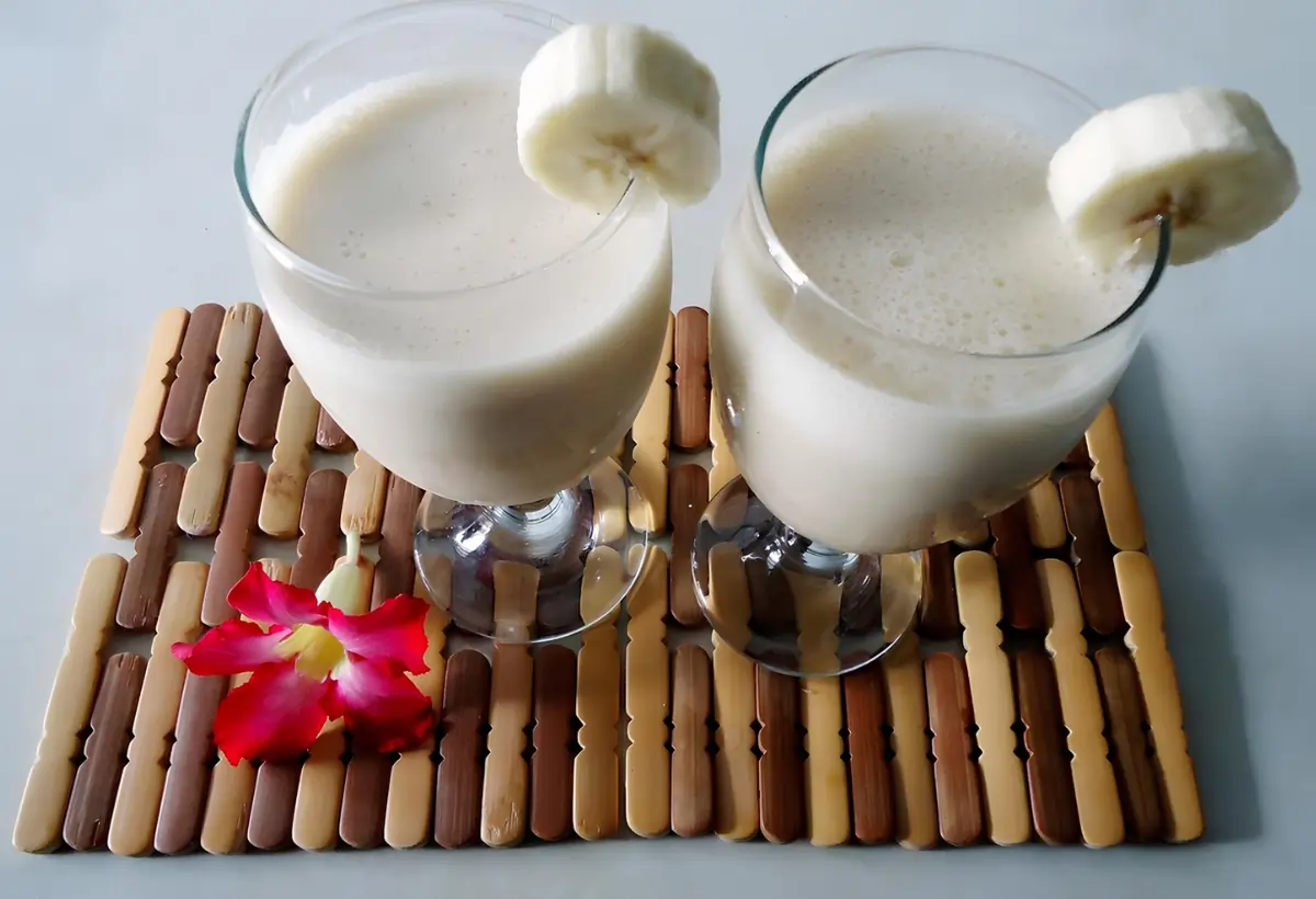 Dois copos de vitamina de banana sem leite em uma mesa decorada.