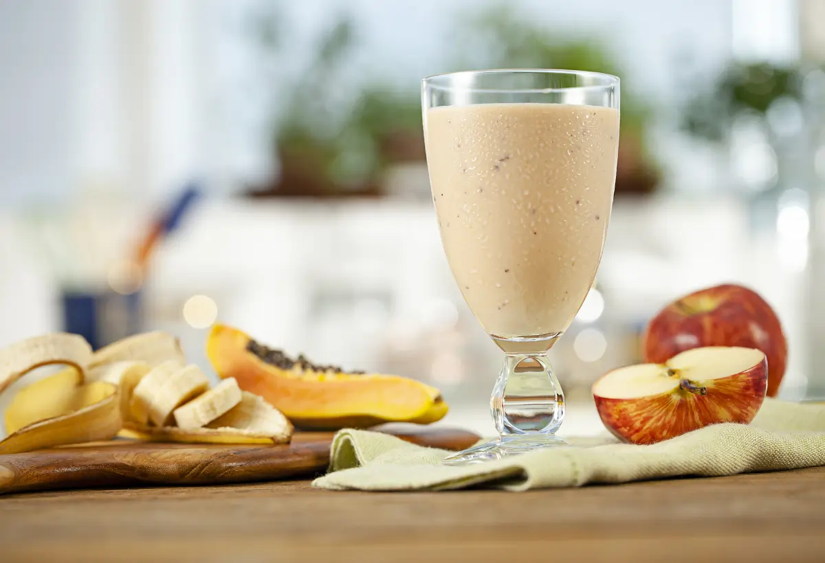 Um copo com uma vitamina sem leite mamão, banana e maça.