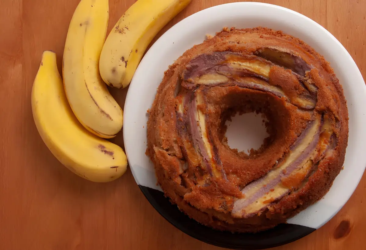 Um prato com um bolo de banana de três bananas ao lado para decorar a mesa.