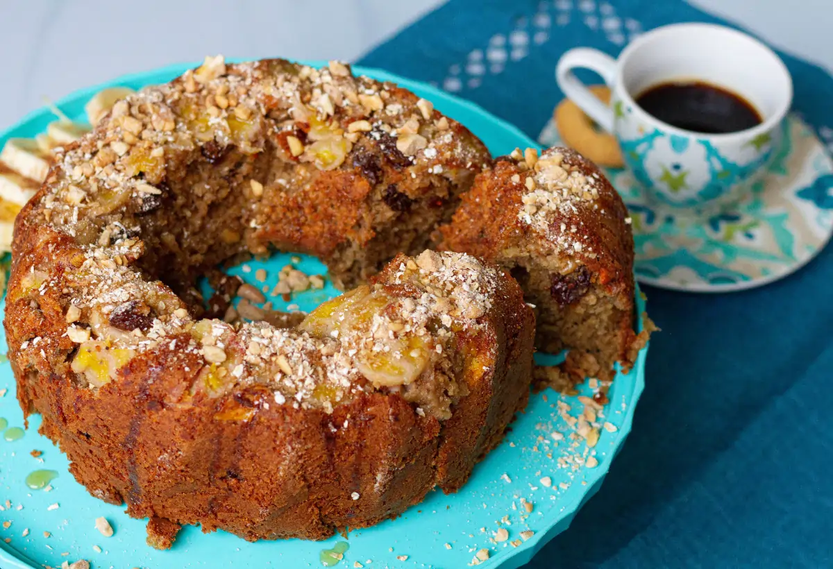 Um bolo de banana com flocos de aveia em uma mesa preparada com café.