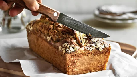 um Bolo de Banana sem Óleo em uma mesa preparada para café.