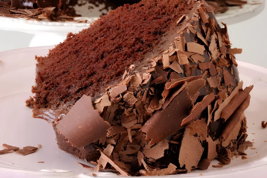 Um prato com uma fatia de bolo de chocolate com raspas de chocolate.