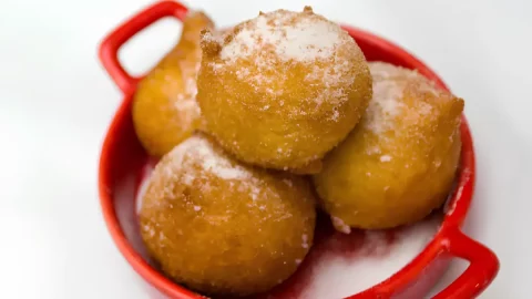 uma panelinha na cor vermelha com bolinhos de chuva.