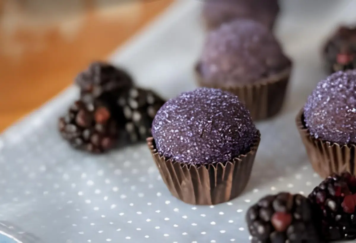 Brigadeiros de amoras em uma mesa decorada.